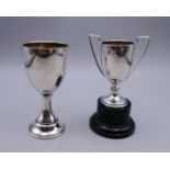 A small silver trophy cup on plinth base and a small silver goblet.