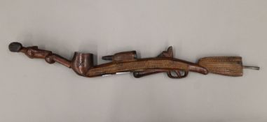 A tribal wooden pipe, carved as a rifle and a nude female. 68 cm long.