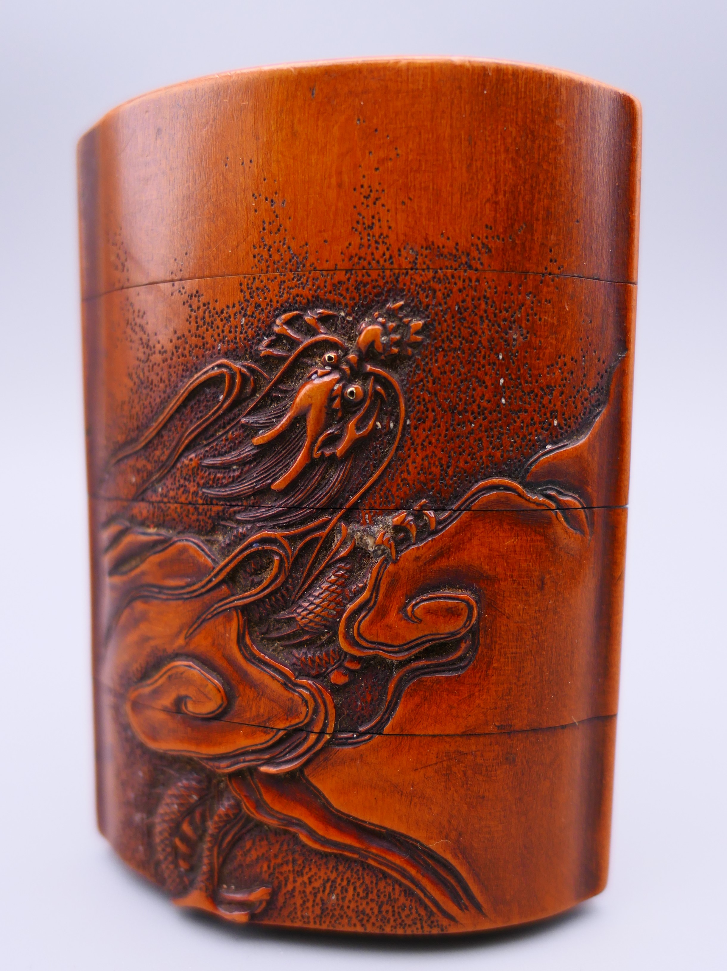 A Japanese carved wooden inro depicting mountains and a dragon amongst clouds. 7.5 cm x 5.5 cm.