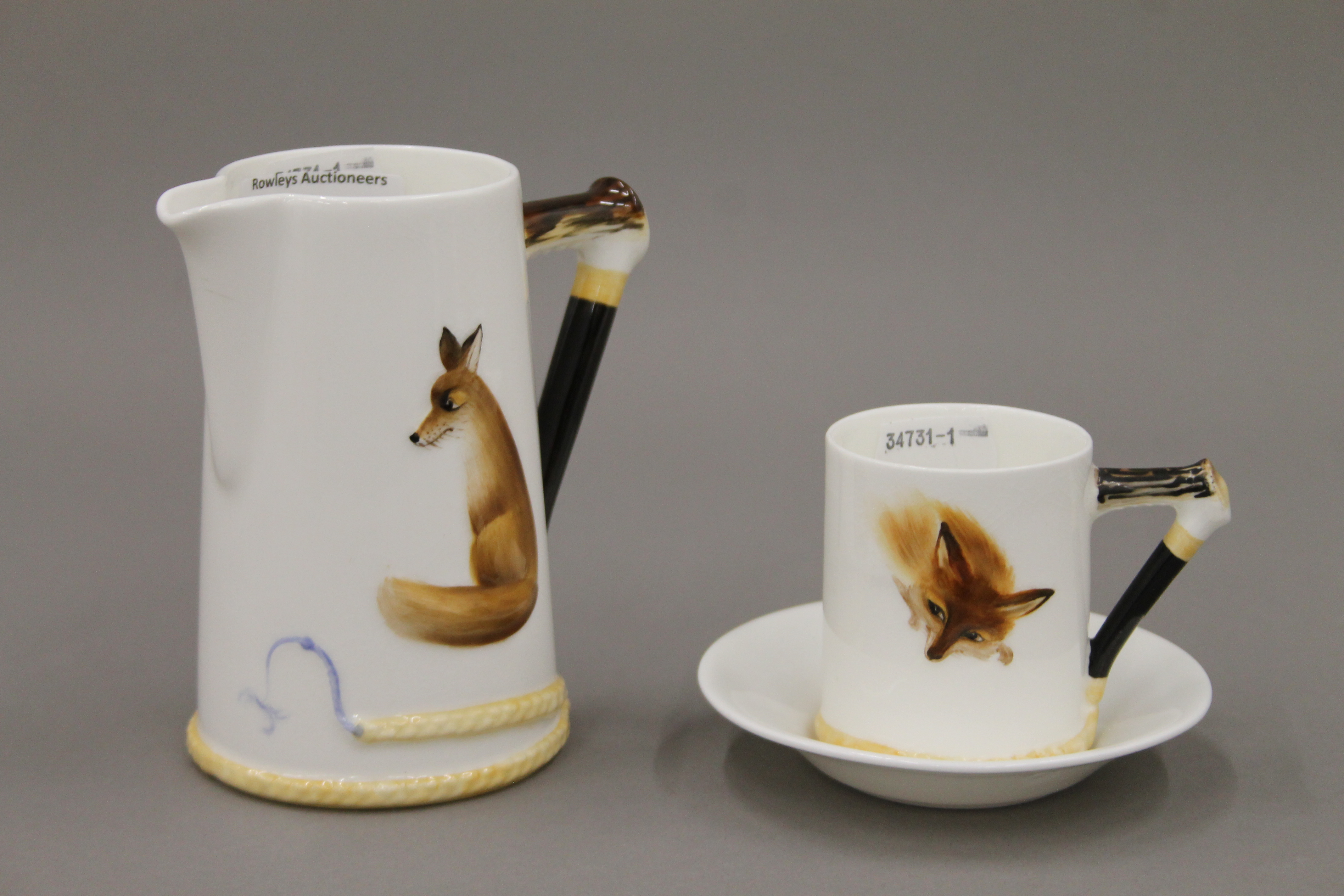 A Royal Doulton Reynard the Fox coffee can and saucer, and a cream jug. The latter 11 cm high.
