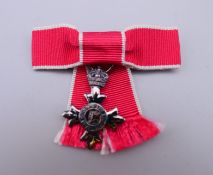 A miniature Order of the British Empire medal with ribbon bow brooch. Medal 3 cm high.