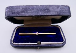 An unmarked gold diamond set bar brooch, boxed. 5 cm long. 2.2 grammes total weight.