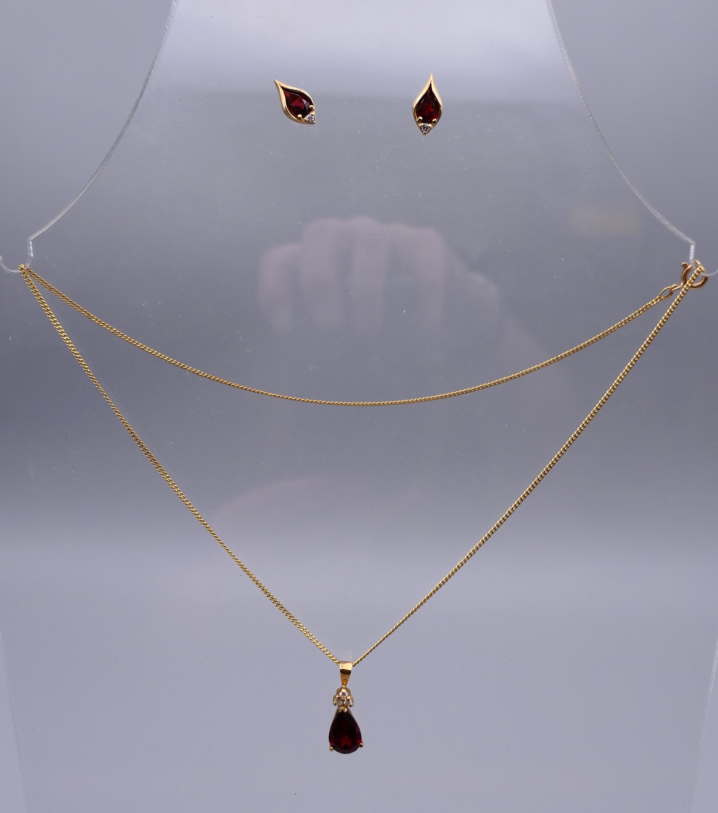 A 9 ct gold garnet pear drop pendant on a gold chain together with a pair of 9 ct gold earrings.