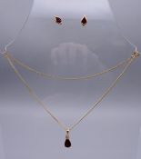 A 9 ct gold garnet pear drop pendant on a gold chain together with a pair of 9 ct gold earrings.
