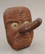 An unusual painted wooden mask with extending nose. 18 cm high.