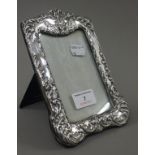 A silver photograph frame embossed with a cherub mask. 19 cm high.