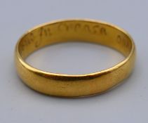 An unmarked high carat, possibly 22 ct gold, posey wedding band,