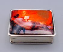 A silver pill box depicting a nude female. 3 cm x 2.5 cm.