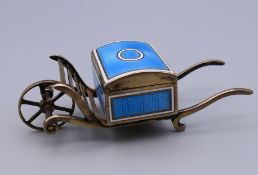 An unmarked silver and enamel stamp box formed as a cart. 8 cm long, 3 cm wide.