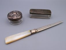 A silver and mother-of-pearl handled paper knife, and two silver topped glass trinket boxes.
