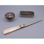 A silver and mother-of-pearl handled paper knife, and two silver topped glass trinket boxes.