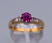 A 9 ct gold red stone ring with diamond chip set shoulders. Ring size P. 2.5 grammes total weight.