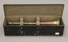 A brass and copper hunting horn with embossed hunt decoration, housed in a toleware case.