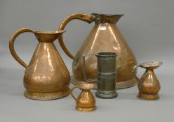 Four antique copper measuring jugs and another.