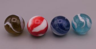 Four antique glass marbles.
