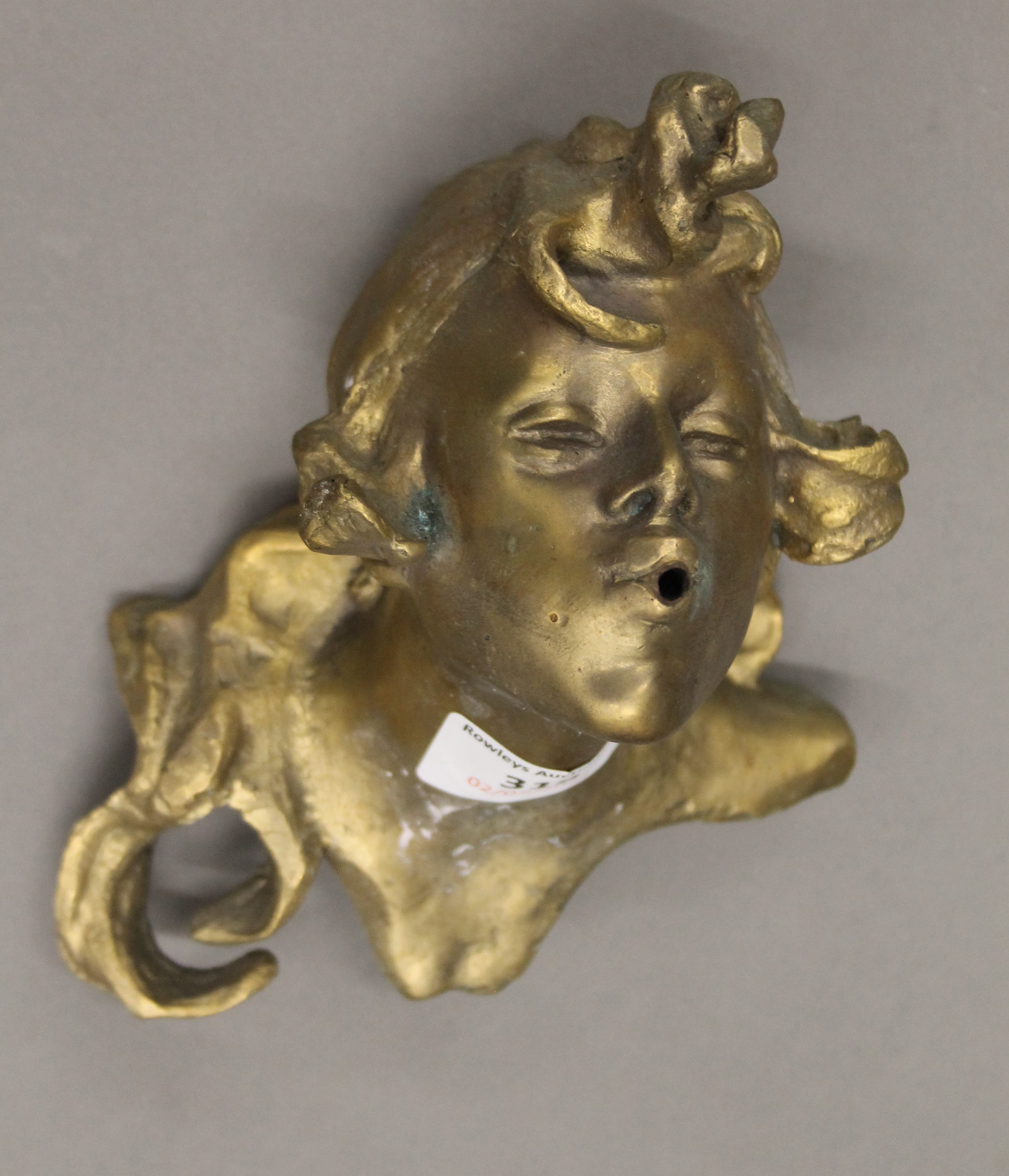 An Art Nouveau style brass spouted wall mask. 16 cm high.