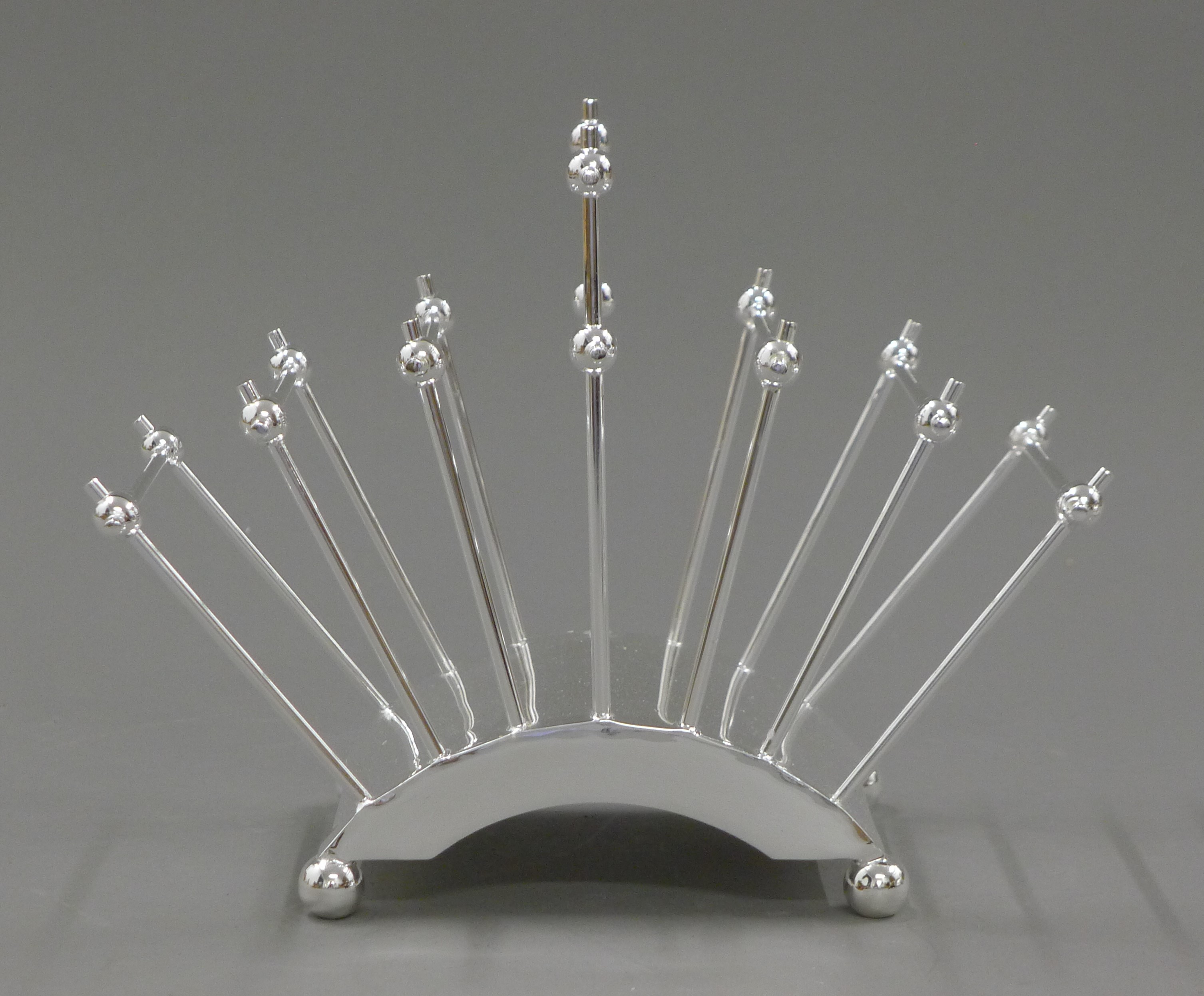 A Christopher Dresser style silver plated toast rack. 22 cm long.