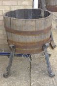 A vintage half barrel planter with wrought iron stand.