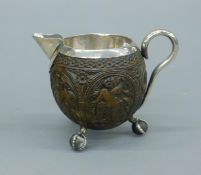 An unmarked silver lined carved coconut jug. 10 cm high.