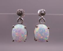 A pair of silver and opal earrings. 1 cm high overall.