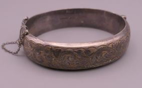 A silver hinged bangle with engraved decoration. 6.5 cm wide. 24.8 grammes.