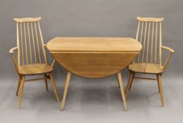 A blonde Ercol drop leaf table and two chairs. The table 112 cm long.