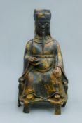 A bronze model of a seated deity holding money. 22.5 cm high.