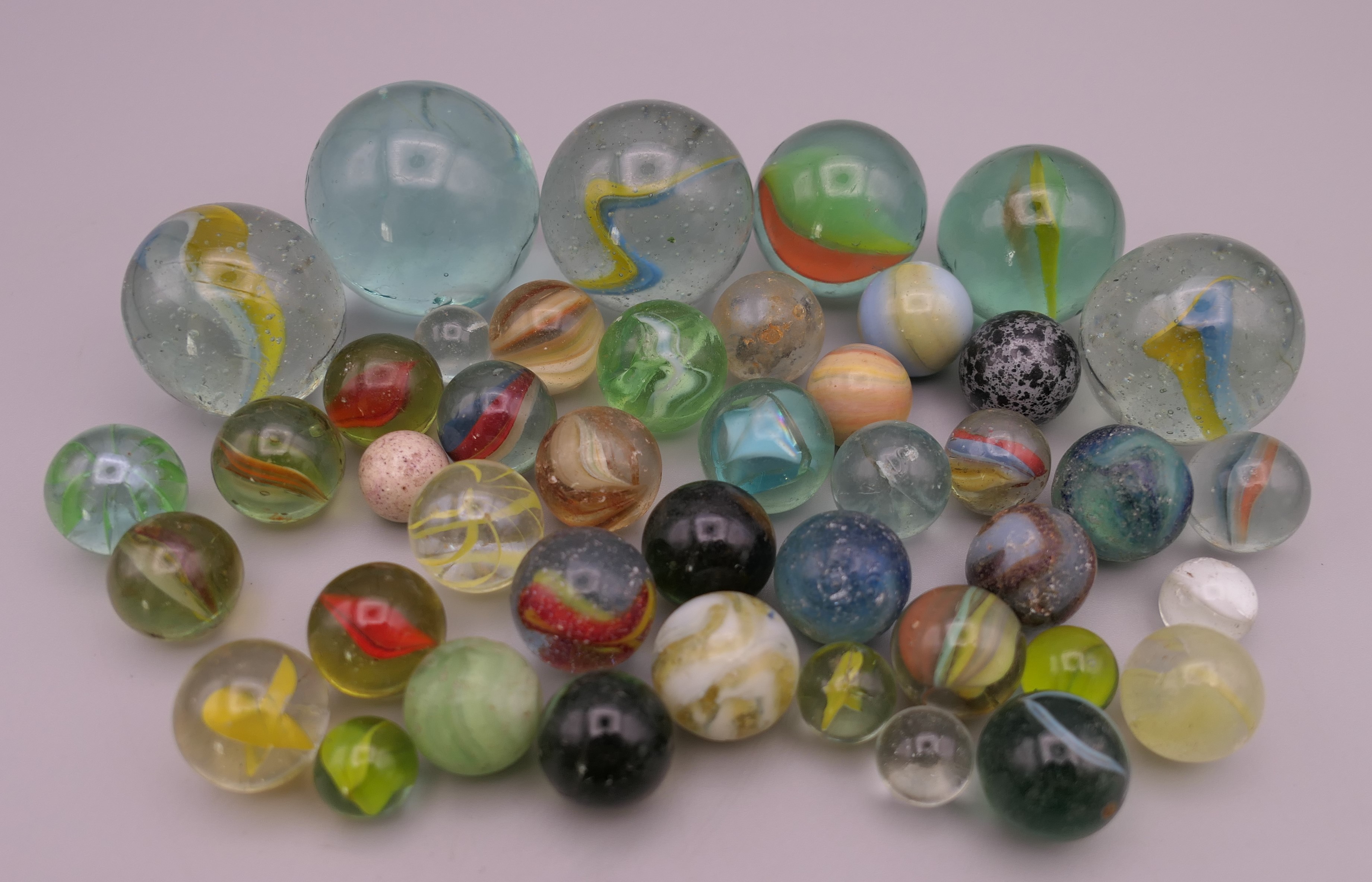 Four antique glass marbles (three approximately 1 inch diameter and the other 15/16th of an inch