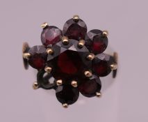 A 9 ct gold garnet flowerhead ring. Ring size O. 4.6 grammes total weight.