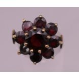 A 9 ct gold garnet flowerhead ring. Ring size O. 4.6 grammes total weight.