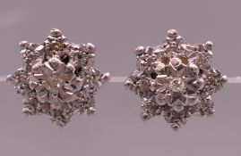 A pair of unmarked two tone gold diamond flowerhead earrings. 1.2 cm diameter. 3.