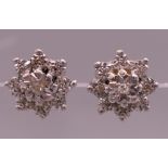 A pair of unmarked two tone gold diamond flowerhead earrings. 1.2 cm diameter. 3.