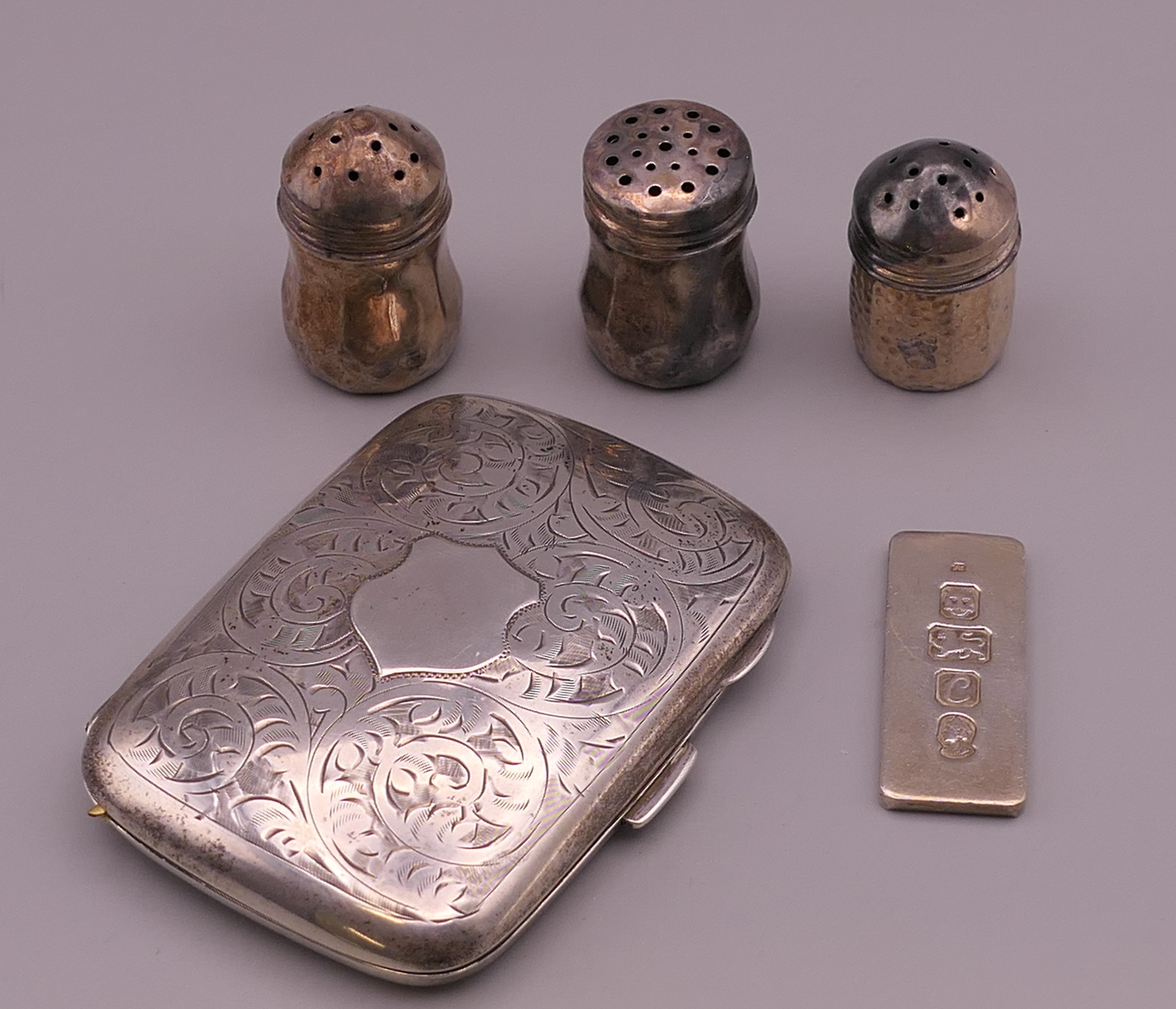 A silver cigarette case, three silver peppers and a silver ingot. The former 6 cm wide. 68.