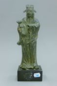 A Chinese Ming bronze attendant, mounted on a later plinth base. 31 cm high.