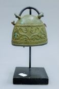 A bronze bell on stand. 22 cm high overall.