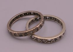 Two unmarked white metal clear stone eternity rings. Ring size N and P. 3.9 grammes total weight.