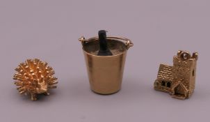 Three 9 ct gold charms comprising an opening church, a hedgehog and a champagne ice bucket.