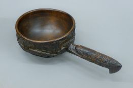 A carved wooden scoop, the handle formed as an eagle. 35 cm long.