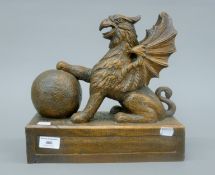 A Victorian carved oak model of a Griffon with a ball, standing on an integral plinth base.