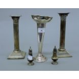 A pair of silver candlesticks, two silver peppers and a plated vase. The former 23 cm high.