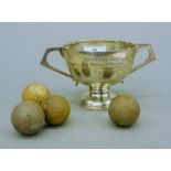 A silver golf trophy cup and four golf balls. The cup 9 cm high. The cup 171.1 grammes.