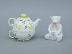 A Belleek porcelain teapot and cup, and a Belleek teddy bear. The latter 11 cm high.