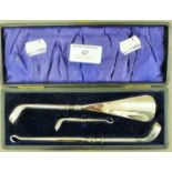A cased set of button hooks and a shoe horn, the silver handles formed as golf clubs. The box 20.