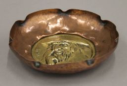 An Arts and Crafts hammered copper and brass dish depicting Charles Dickens 'Fagin'. 13 cm diameter.