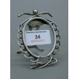 A small silver photograph frame decorated with golf clubs. 8 cm high.