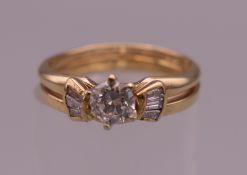A 14 K gold diamond ring, the central claw set stone flanked by baguette set shoulders.