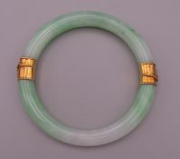An unmarked high ct gold mounted jade bangle. 7 cm interior diameter.