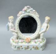 A porcelain mirror with putto. 28 cm high.