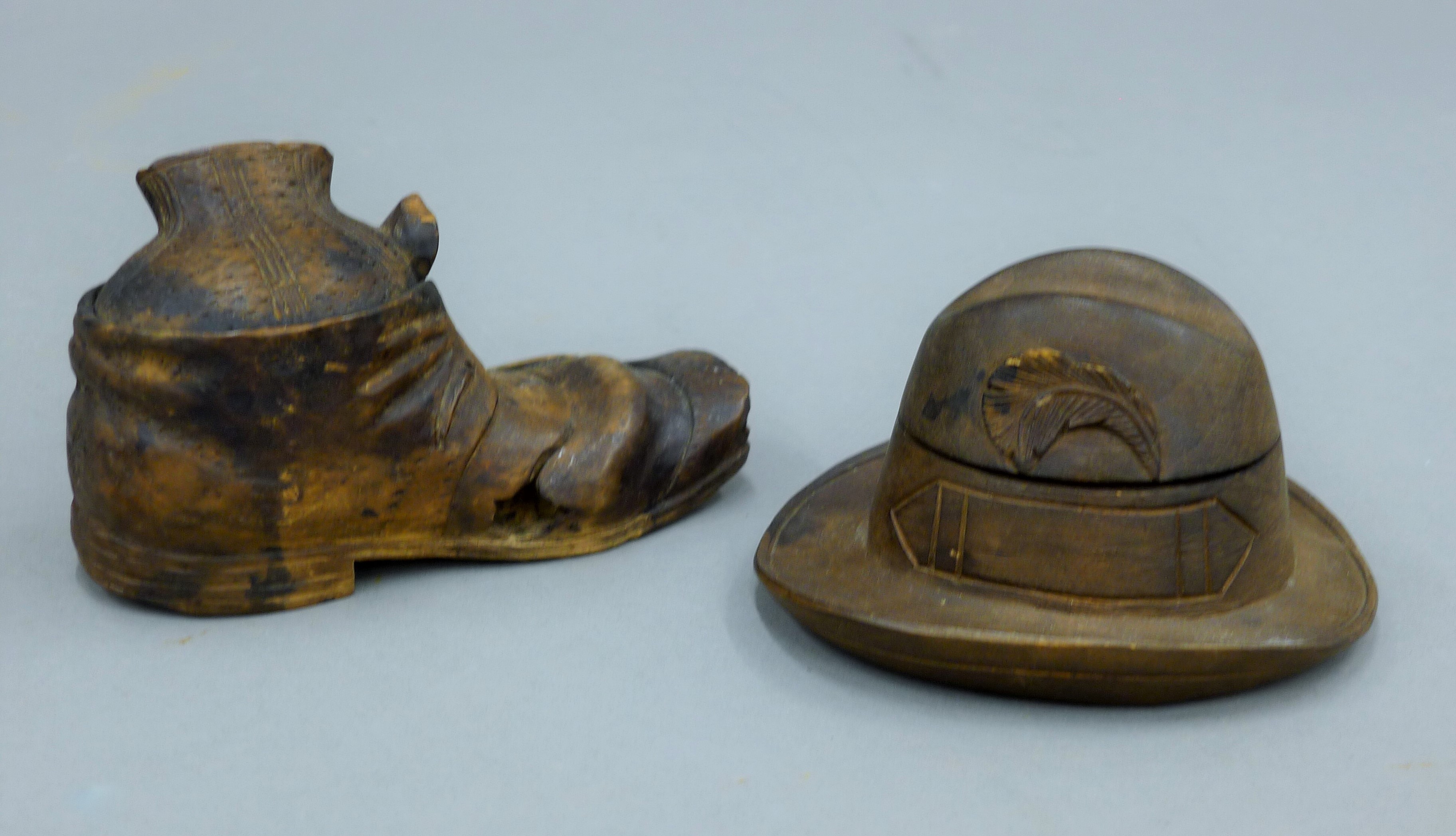 A carved wooden boot form inkwell and a hat form inkwell. The former 13 cm long.