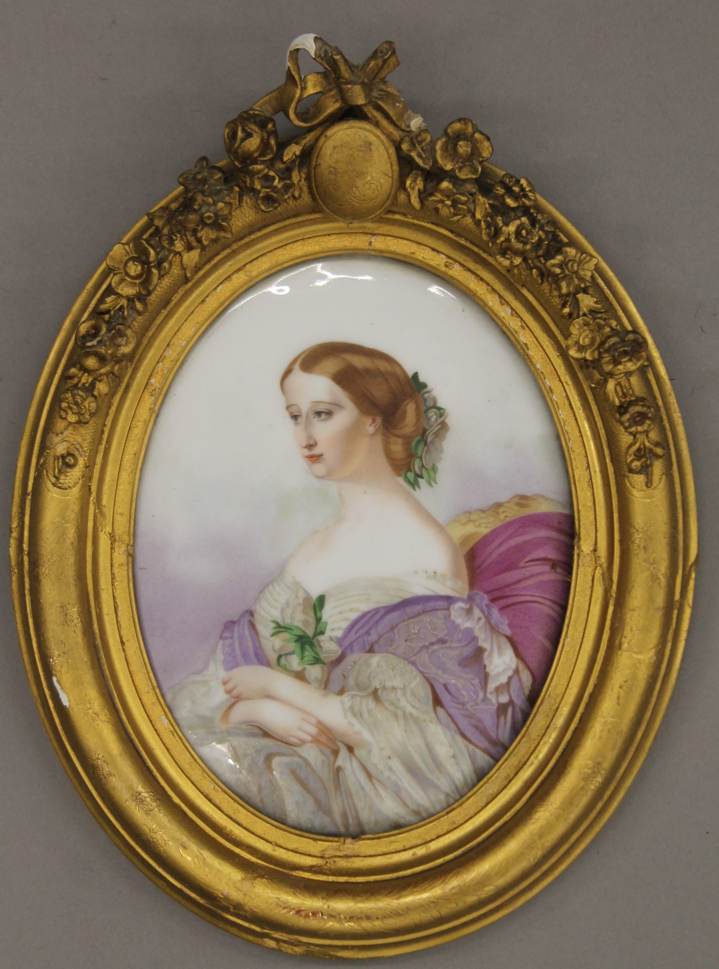 A 19th century Continental plaque painted with a seated lady, housed in an oval gilt frame.